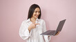© Krakenimages.com - Young beautiful hispanic woman smiling confident pointing to laptop over isolated pink background