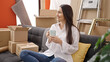 © Krakenimages.com - Young beautiful hispanic woman drinking coffee sitting on sofa at new home