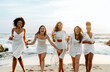 © Prostock-studio - Bride's team. Group of happy ladies dancing and having fun on the beach, having hen party at coastline