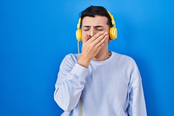 Poster - Non binary person listening to music using headphones bored yawning tired covering mouth with hand. restless and sleepiness.