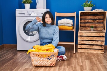 Poster - Young hispanic woman at laundry room with angry face, negative sign showing dislike with thumbs down, rejection concept