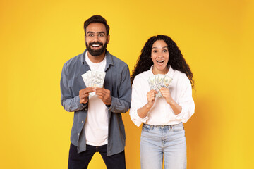 Wall Mural - Rich Middle Eastern Spouses Holding Money Dollar Cash, Yellow Background