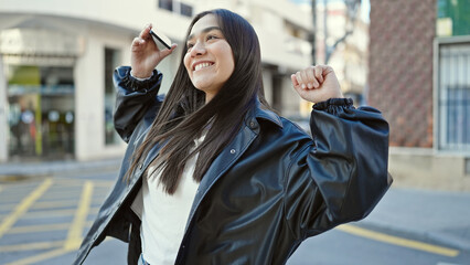 Wall Mural - Young beautiful hispanic woman smiling confident using smartphone dancing at street