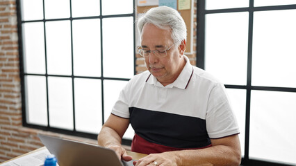 Canvas Print - Middle age man with grey hair business worker using laptop with serious face at office