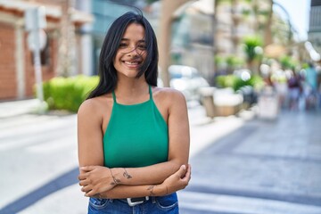 Canvas Print - Young hispanic woman smiling confident standing with arms crossed gesture at street