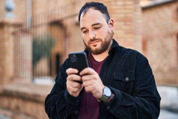 Wall Mural - Young hispanic man using smartphone at street