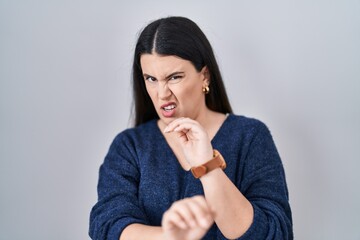 Sticker - Young brunette woman standing over isolated background disgusted expression, displeased and fearful doing disgust face because aversion reaction.