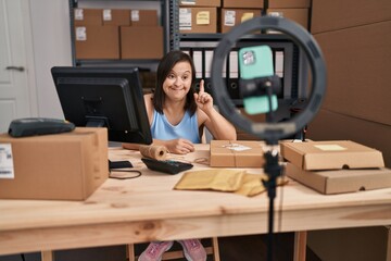 Sticker - Hispanic girl with down syndrome working at small business ecommerce doing online tutorial surprised with an idea or question pointing finger with happy face, number one