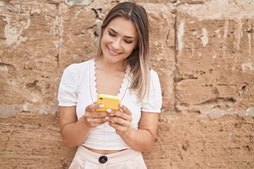 Sticker - Young caucasian woman smiling confident using smartphone over isolated brick background