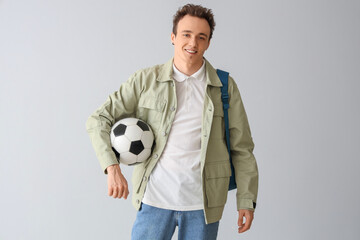 Poster - Male student with backpack and soccer ball on grey background