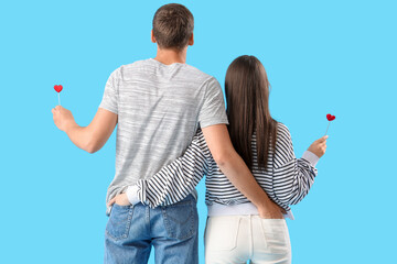 Sticker - Happy young couple with hearts on blue background, back view