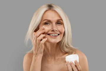 Wall Mural - Skincare Routine. Beautiful Mature Woman Applying Moisturizing Cream On Face