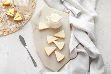 Wall Mural - Board with triangles of tasty processed cheese and milk on light background