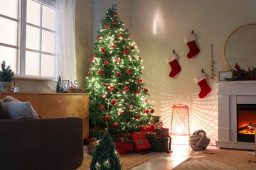 Wall Mural - Christmas tree with gifts, glowing lights and fireplace in dark living room