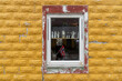 une fenêtre sur un mur jaune , avec des objets et un fagnon norvégien vu à travers 