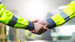 © ihorvsn - Close up of business gesture of Caucasian men shaking hands at factory. Sign of agreement and cooperation together. Indoor. Males constructors or builders shake hands. Gesture of agreeing of workmen.