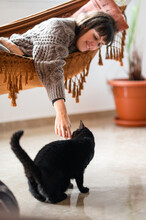 Woman Stroking Fluffy Black Cat On Floor