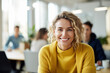 © ADDICTIVE STOCK - Generative AI image of portrait of smiling young female employee with blonde hair looking at camera while sitting with colleagues in blurred and illuminated cafe zone in daylight
