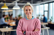 © ADDICTIVE STOCK - Generative AI image of portrait of smiling adult female employee in sweater looking at camera while standing with hands crossed in blurred and illuminated office with colleagues