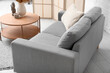 © Pixel-Shot - Cozy grey sofa with pillow and coffee table near white brick wall