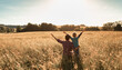 © kieferpix - Joyful father son bonding amidst wheat field, arms raised, connecting with nature, under sunny sky.