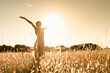 canvas print picture - Joyful Person Raising Arms morning  in Rural Field Under Summer Sunlight