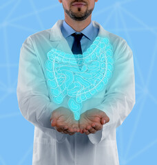 Poster - Gastroenterologist holding illustration of intestines on light blue background, closeup