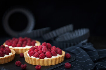 Wall Mural - Delicious raspberry mini tarts (tartlets) with whipped cream on dark background