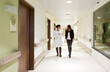 © Designpics - Doctor explaining something to a patient while walking through a hospital corridor.