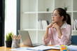 © Phimwilai - Confident Asian businesswoman using laptop computer working in office with calculator papers on table make a plan analyzing financial reports business plan investment analytical concept.