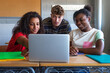 © Daniel - Multiracial group of high school students doing homework research together using laptop in class.