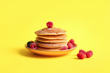 Wall Mural - Plate of tasty pancakes with raspberries on yellow background