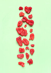 Pieces of fresh raspberries on green background