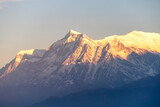 Fototapeta Góry - Machhapuchhre Peak, the sunrise area of annapurna base camp, Nepal, is a very beautiful peak of the Himalayas. snow capped peaks photo from a distance The red-orange morning sun shines brightly.