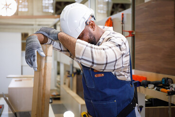 black male carpenter Tired stressed out from the hot summer weather in the furniture carpentry room.