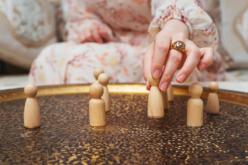 girl with wooden figurines of people on the table. subject photo session of humanoid toys in the room. wooden toys in the hands of a woman on a bronze plate