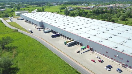 Sticker - Aerial view of goods warehouse. Logistics center in industrial city zone from above. Aerial view of trucks loading at logistic center. View from drone.