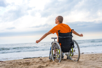 A disabled person on his back in a wheelchair on the beach feeling free by the sea