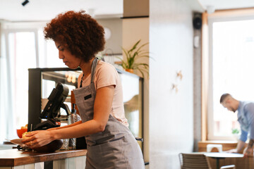 Wall Mural - African waitress carrying plates with meal while working in cafe