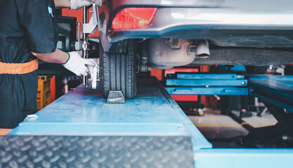 Sticker - Asian skilled technician adjusts in garage after mounting each tire for driving center and aligning wheels near wheel center.