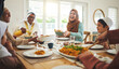 © Azee/peopleimages.com - Food, funny and muslim with big family at table for eid mubarak, Islamic celebration and lunch. Ramadan festival, culture and iftar with people laughing at home for fasting, islam or religion holiday