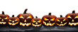 © Duncan Andison - A group of seven lit spooky halloween pumpkins, Jack O Lantern with evil face and eyes on a table isolated against a transparent background.