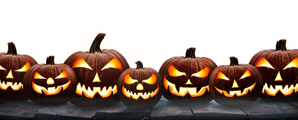 Wall Mural - A group of seven lit spooky halloween pumpkins, Jack O Lantern with evil face and eyes on a table isolated against a transparent background.