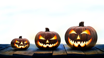Wall Mural - three lit jack-o-lantern, halloween pumpkin lanterns on a wooden product display table with an isola
