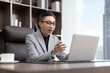 © Blue Jean Images - Successful Chinese businessman using laptop in office