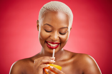 Wall Mural - Happy black woman, orange and vitamin C for diet or natural nutrition against a red studio background. African female person smile and drinking organic citrus fruit with straw on mockup space