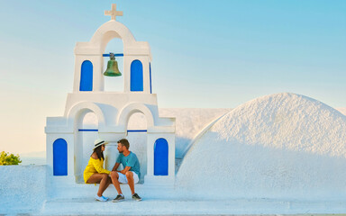 Wall Mural - Young couple of men and women tourists visit Oia Santorini Greece on a sunny day during summer with whitewashed homes and churches, Greek Island Aegean Cyclades