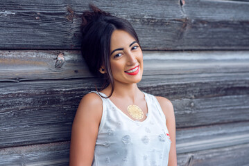 Girl brunette in a park in the summer resting white blouse on the background of a wooden fence, fashion lifestyle, gentle look. Sensual make-up, tanned skin and bright red lipstick. Portrait of a woma