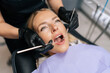 © dikushin - Closeup portrait of blonde female patient getting dental treatment in modern clinic, dentist doctor examining teeth of young woman with sterile tools in dentistry cabinet. Concept of dental health.
