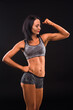 © Designpics - Brunette fitness lady showing her beautiful and muscular body while posing isolated on black background in studio. Sports and fitness concepts.